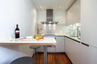 a kitchen with white cabinets and a table with wine glasses at Inside Barcelona Apartments Mercat in Barcelona