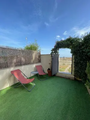 two chairs sitting on a patio with green grass at Beach flat with garden in Castelldefels