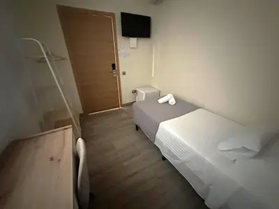a hotel room with two beds and a door at Hostal Balmes Centro in Barcelona