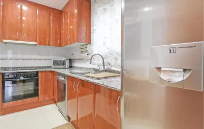 a kitchen with wooden cabinets and a stainless steel refrigerator at Nice Home In St Cebrià De Vallalta in Sant Cebrià de Vallalta