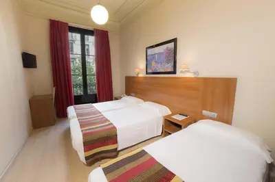 a hotel room with two beds and a window at Ciudad Condal Hostal - Paseo de Gracia in Barcelona