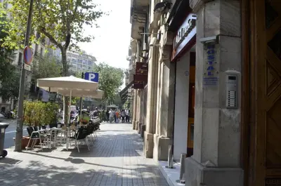 a street with tables and chairs and an umbrella at Ciudad Condal Hostal - Paseo de Gracia in Barcelona