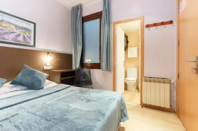 a bedroom with a large bed and a bathroom at Ciudad Condal Hostal - Paseo de Gracia in Barcelona