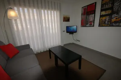 a living room with a couch and a table and a tv at Sitges Apartment in Sitges