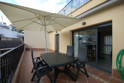 a patio table and chairs with an umbrella on a balcony at Sitges Apartment in Sitges