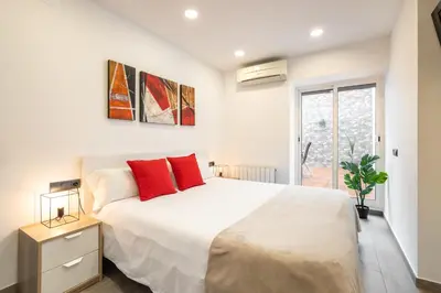 a bedroom with a large white bed with red pillows at Luxury Beach Apartment, next to the sea in Premiá de Mar