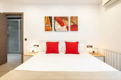 a bedroom with a white bed with red pillows at Luxury Beach Apartment, next to the sea in Premiá de Mar