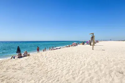 a group of people sitting on a beach at Luxury Beach Apartment, next to the sea in Premiá de Mar