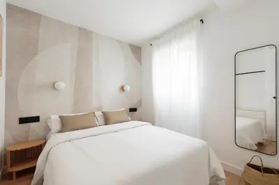 a white bedroom with a white bed and a mirror at Vibe Apartments by Olala Homes in Hospitalet de Llobregat