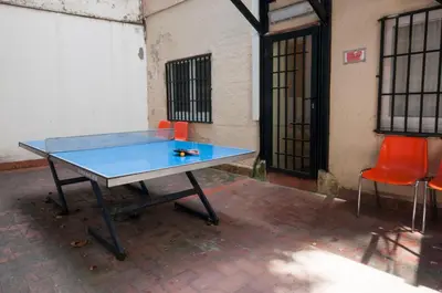 a blue ping pong table with two orange chairs at Studio Hostel in Barcelona