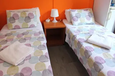 a bedroom with two beds and a table with a lamp at Pensión Arosa in Barcelona