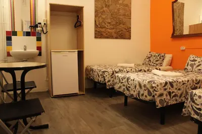 a room with two beds and a sink and a table at Pensión Arosa in Barcelona