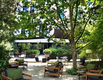 a patio with chairs and tables and a tree at Alma Barcelona GL in Barcelona