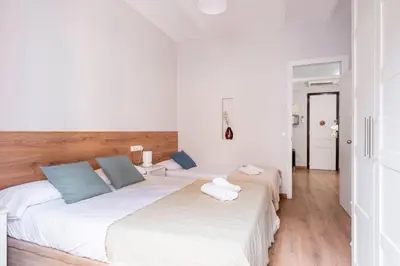 two beds in a room with white walls and wooden floors at Fira Barcelona Apartment in Hospitalet de Llobregat