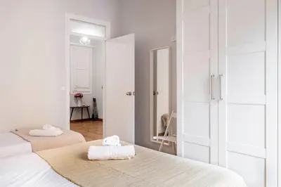 a white bedroom with two beds with towels on them at Fira Barcelona Apartment in Hospitalet de Llobregat