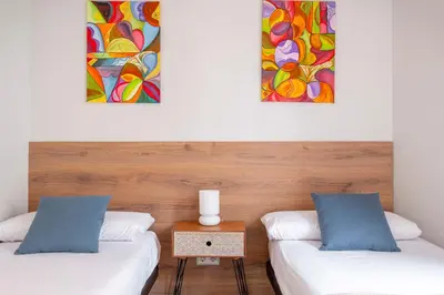 two beds in a room with paintings on the wall at Fira Barcelona Apartment in Hospitalet de Llobregat