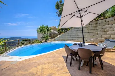 a table with an umbrella next to a swimming pool at Catalunya Casas Modern Magnificence , only a few km to the beach! in Sant Cebrià de Vallalta