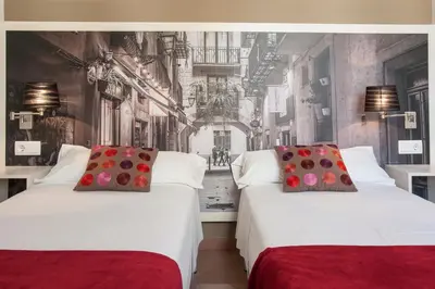 two beds in a room with a wall mural at BCNGOTIC 22 in Barcelona