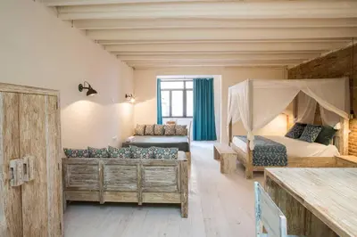 a bedroom with two beds and a couch in a room at La Bodega Suites in Hospitalet de Llobregat