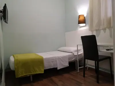a small room with a bed and a table and a chair at Hostal Lesseps in Barcelona