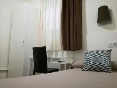 a bedroom with a bed and a chair and a desk at Hostal Lesseps in Barcelona