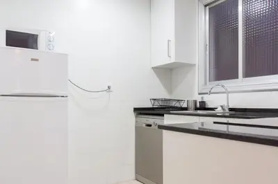 a white kitchen with a sink and a window at Charm Apartment Sagrada Familia in Barcelona