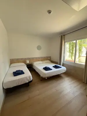 two beds in a room with a window at Hostal Casa Torrent in Canet de Mar