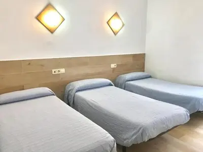a room with three beds and lights on the wall at Hostal Casa Torrent in Canet de Mar