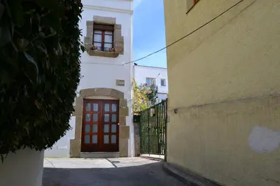 an alley with a red door and a building at Hostal Casa Torrent in Canet de Mar
