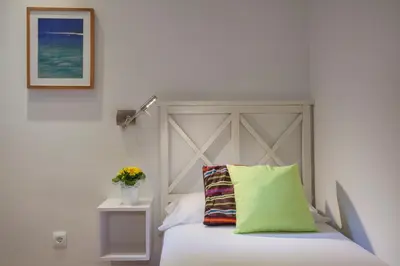 a bed with a gray headboard and a green pillow at BCNGOTIC43 in Barcelona