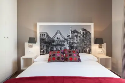 a bedroom with a white bed with a painting on the wall at BCNGOTIC43 in Barcelona