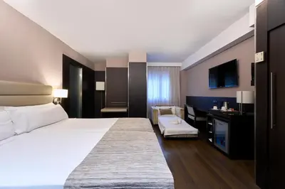 a hotel room with a large bed and a desk at Catalonia Rigoletto in Barcelona