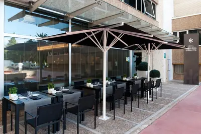 a restaurant with black tables and chairs under an umbrella at Catalonia Rigoletto in Barcelona