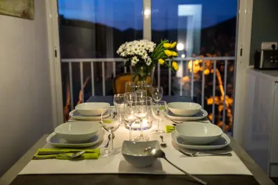a table with plates and glasses and a vase of flowers at Jewel Home in Sant Pere de Ribes