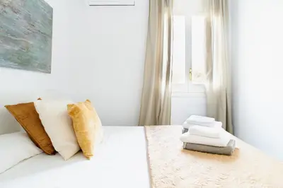 a white bedroom with a bed with white sheets and pillows at Jewel Home in Sant Pere de Ribes