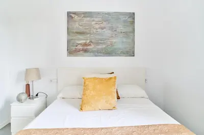 a bedroom with a white bed with a painting on the wall at Jewel Home in Sant Pere de Ribes