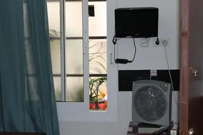 a room with a window with a fan and a television at Central Station Hostel Barcelona in Barcelona