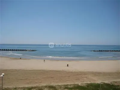 a beach with people walking on the sand and the ocean at Mar De Cunit in Cunit