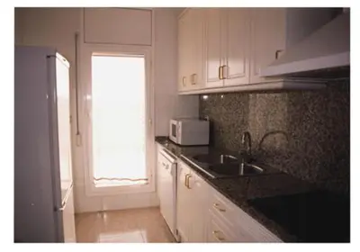 a kitchen with white cabinets and a sink and a window at Mar De Cunit in Cunit