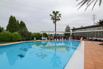 a large blue swimming pool with a palm tree in the background at Hotel Restaurant Sol i Vi in Lavern