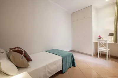 a white bedroom with a bed and a chair at BCNGOTIC 42 in Barcelona