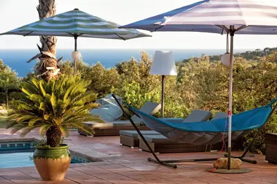 a couple of hammocks and umbrellas next to a pool at Villa Costa Barcelona in Arenys de Munt