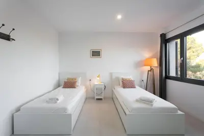 a white room with two beds and a window at Villa Costa Barcelona in Arenys de Munt