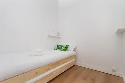 a bed in a room with white walls and wooden floors at Flateli Providencia in Barcelona