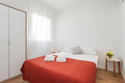 a white bedroom with a bed with a red blanket at Flateli Providencia in Barcelona