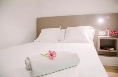a white bed with a towel and a pink flower on it at Hostalet de Barcelona in Barcelona