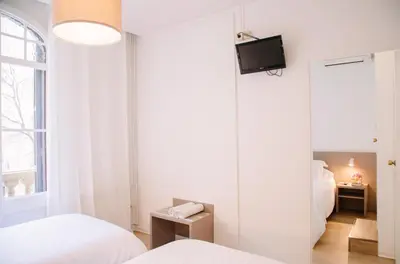 a bedroom with two beds and a tv on a wall at Hostalet de Barcelona in Barcelona