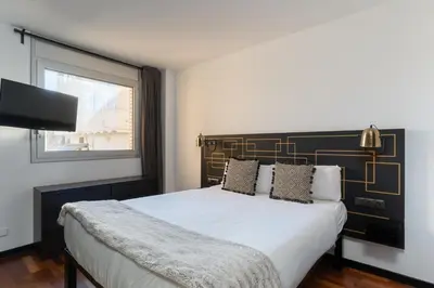 a bedroom with a bed with a black and gold headboard at TSA Sepulveda in Barcelona