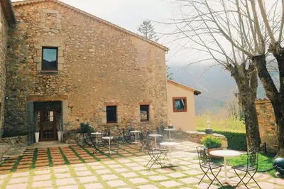 a stone building with tables and chairs in front of it at Sant Marçal del Montseny in Montseny