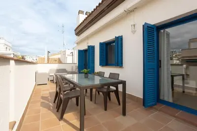 a table and chairs on a balcony with blue shutters at Lucas House Apartments by Sitges Group in Sitges